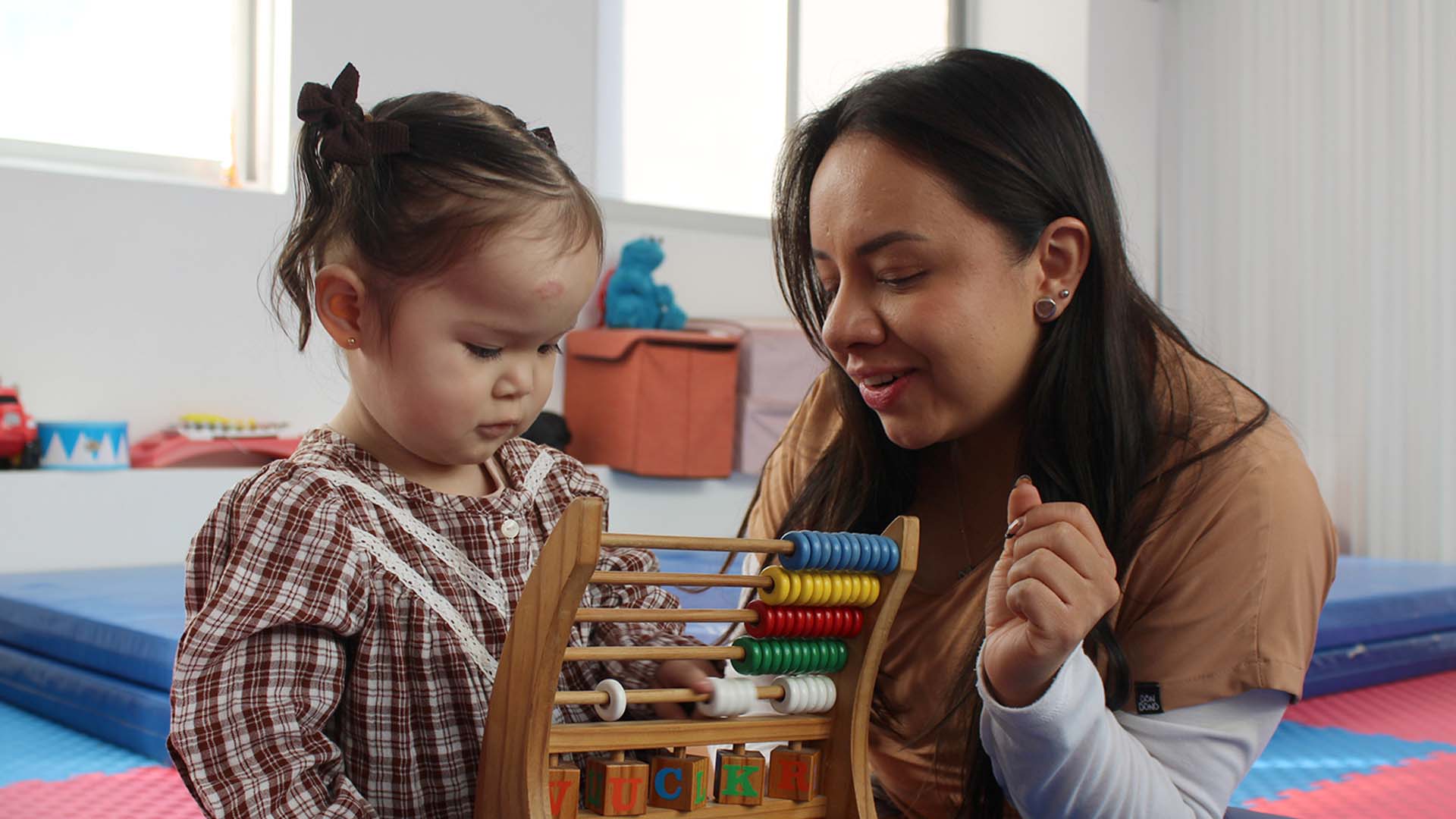 Niña pequeña junto a una especialista durante una sesión de estimulación con un ábaco