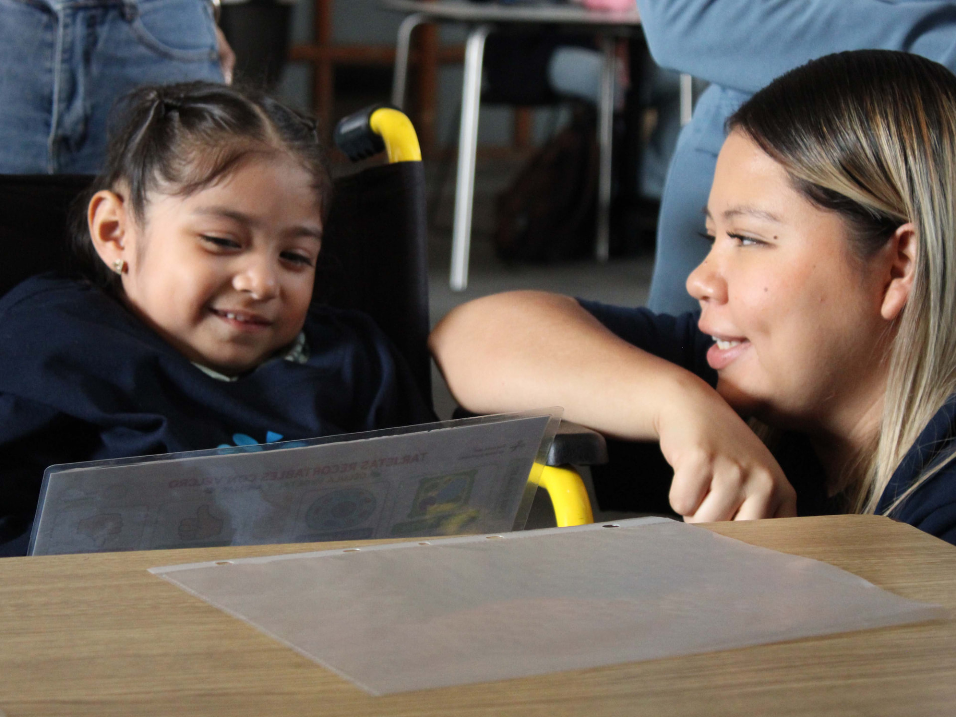 Niña sonriente junto a una adulta revisando un material educativo sobre neurodesarrollo
